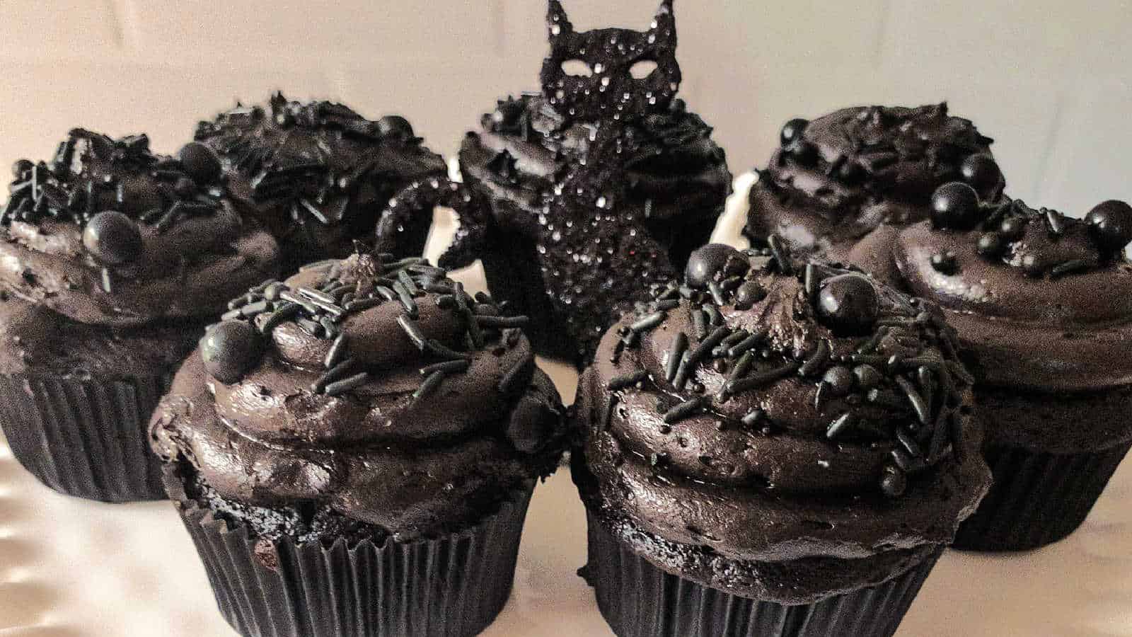 A group of black cupcakes decorated with black frosting.