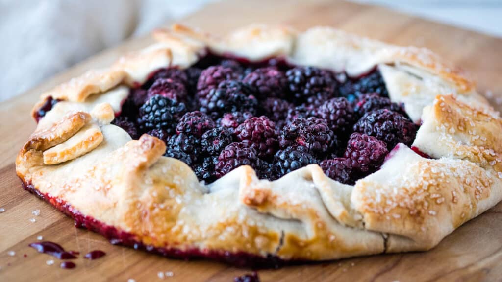 A blackberry galette on a wooden cutting board.