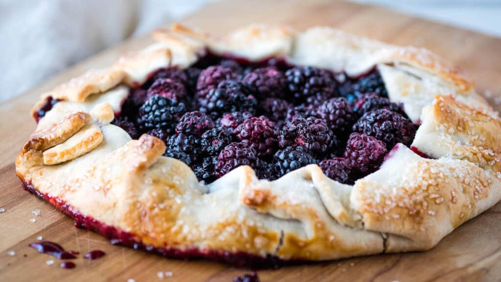A blackberry galette on a wooden cutting board.