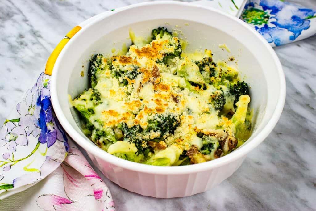 A white bowl with Broccoli and Parmesan Casserole in it.