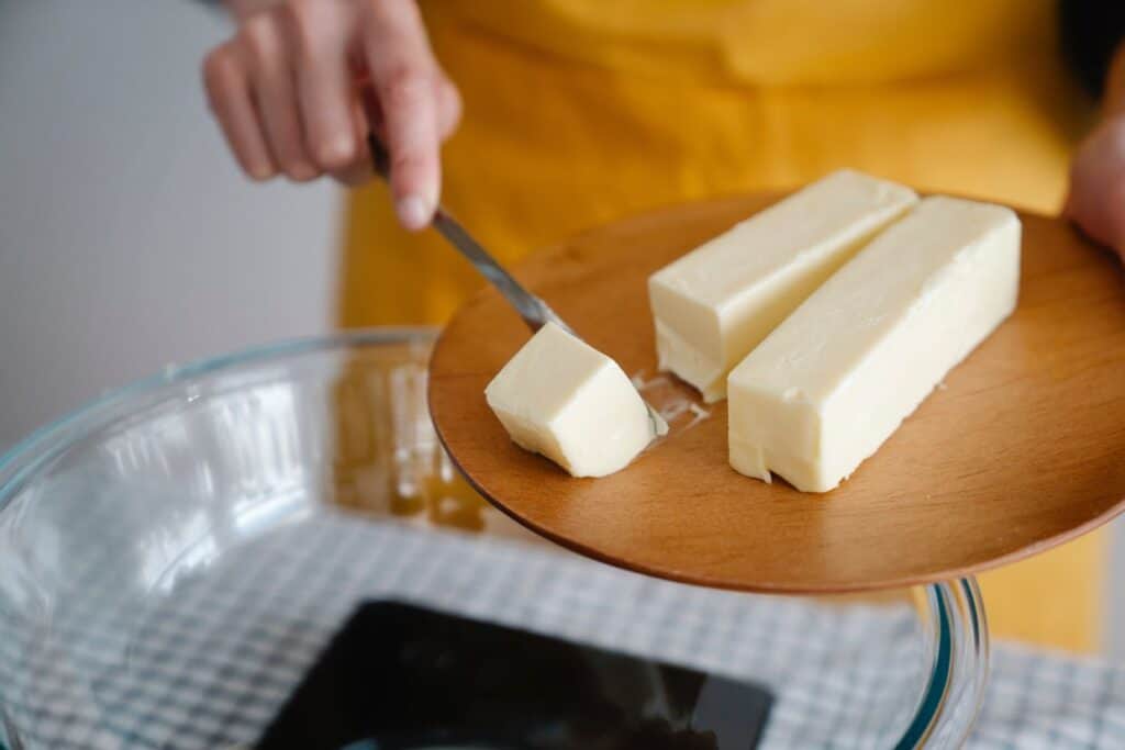 A woman is slicing butter on a plate.