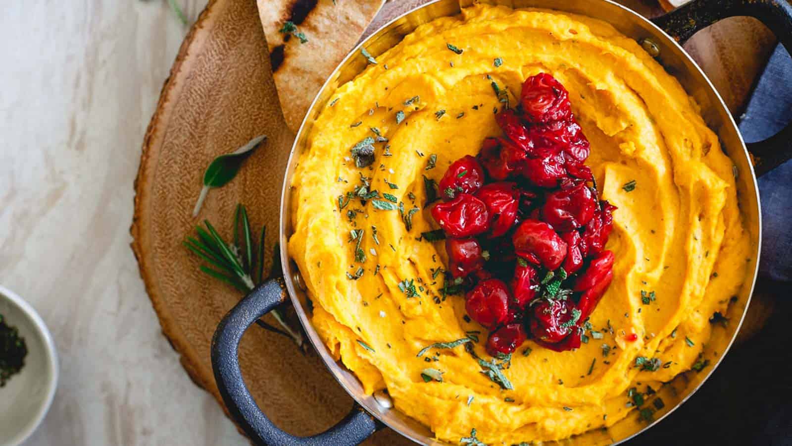Butternut squash goat cheese dip in a bowl with handles topped with cherry compote.