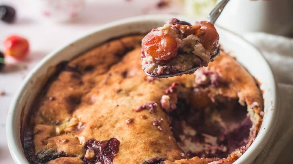 A fruity spoonful of cherry cobbler in a white dish.
