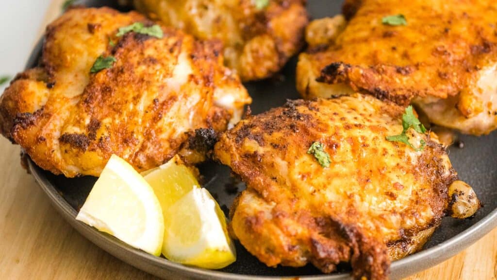 Fried chicken with lemon wedges on a plate.