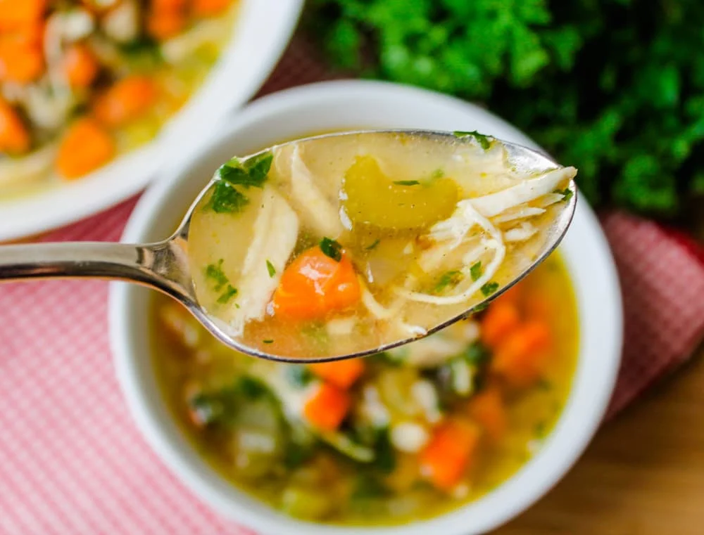 A spoonful of chicken soup with quinoa and veggies.