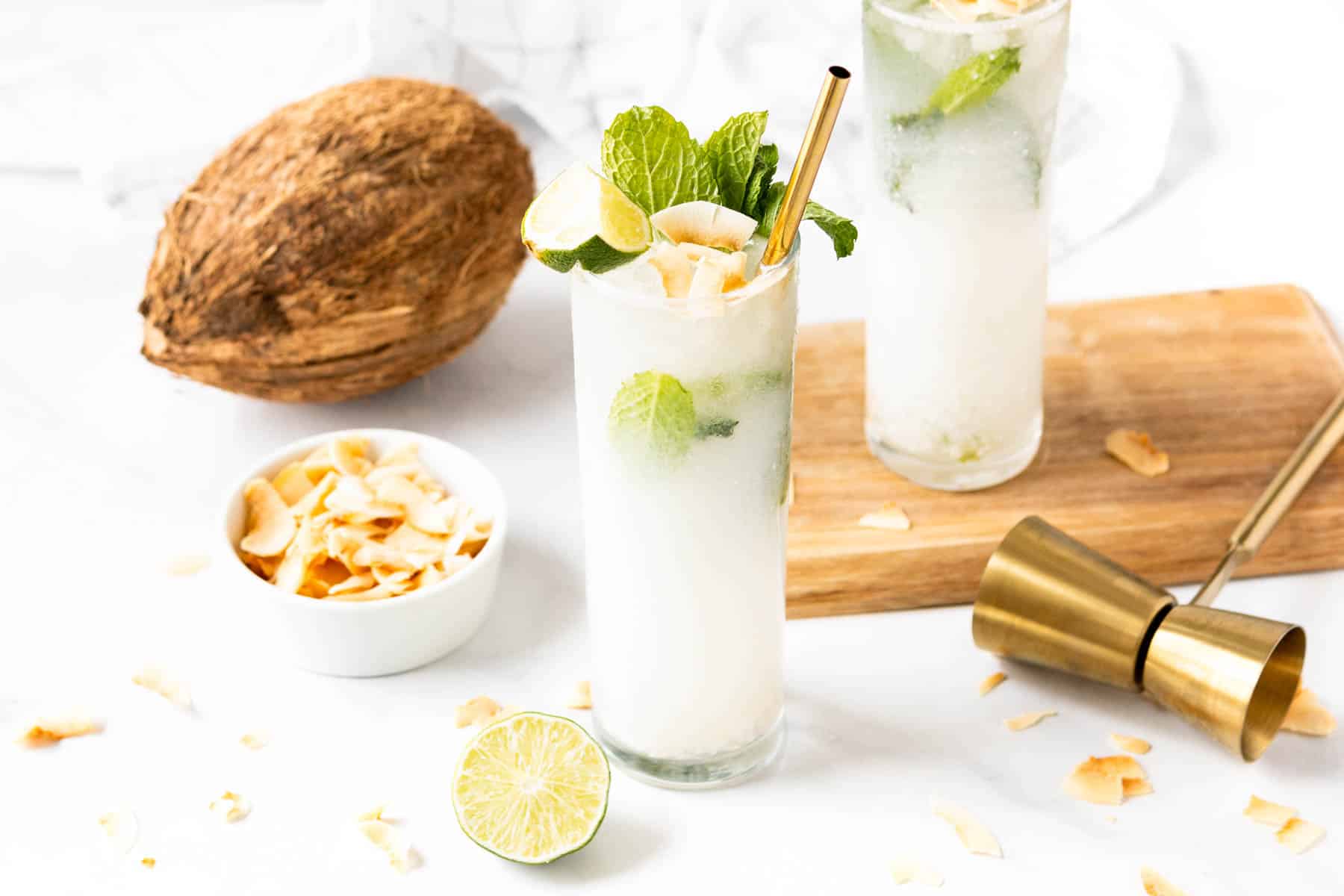 A coconut mojito with lime and mint leaves on a wooden board.