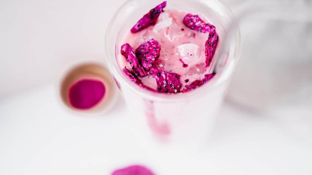 A pink drink with pink sprinkles and a straw.