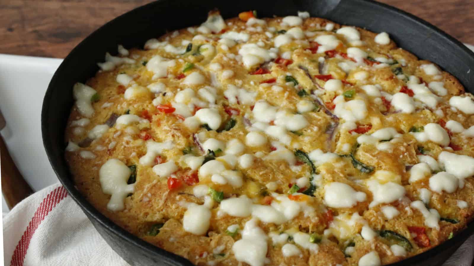 Iron skillet cornbread filled with vegetables and cheese.