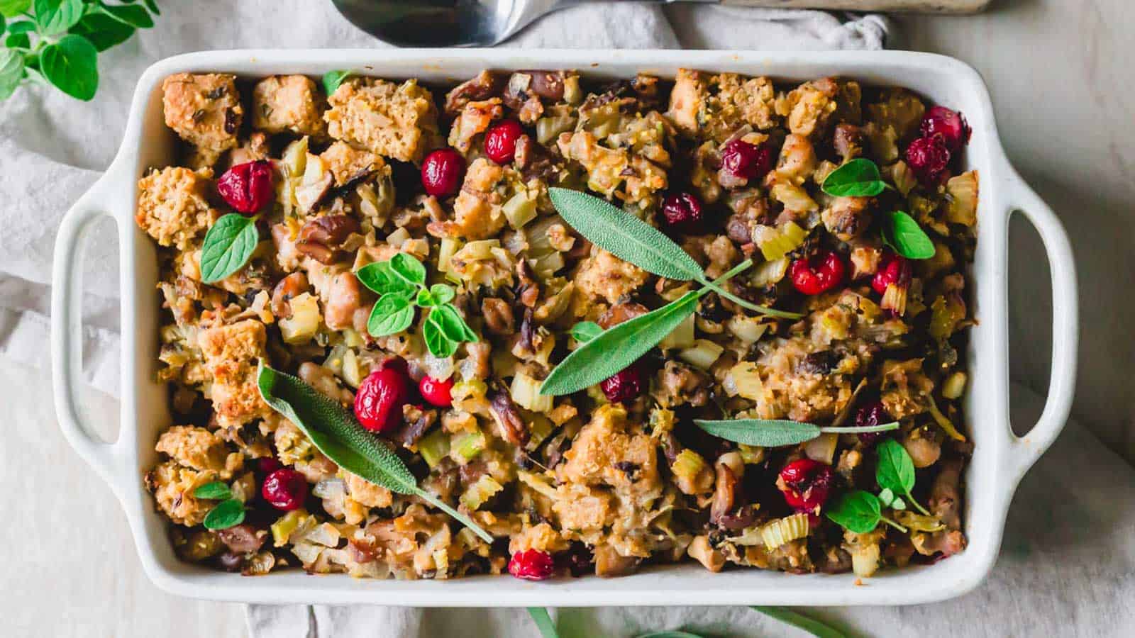Cornbread chestnut stuffing in a white baking dish garnished with fresh sage leaves.