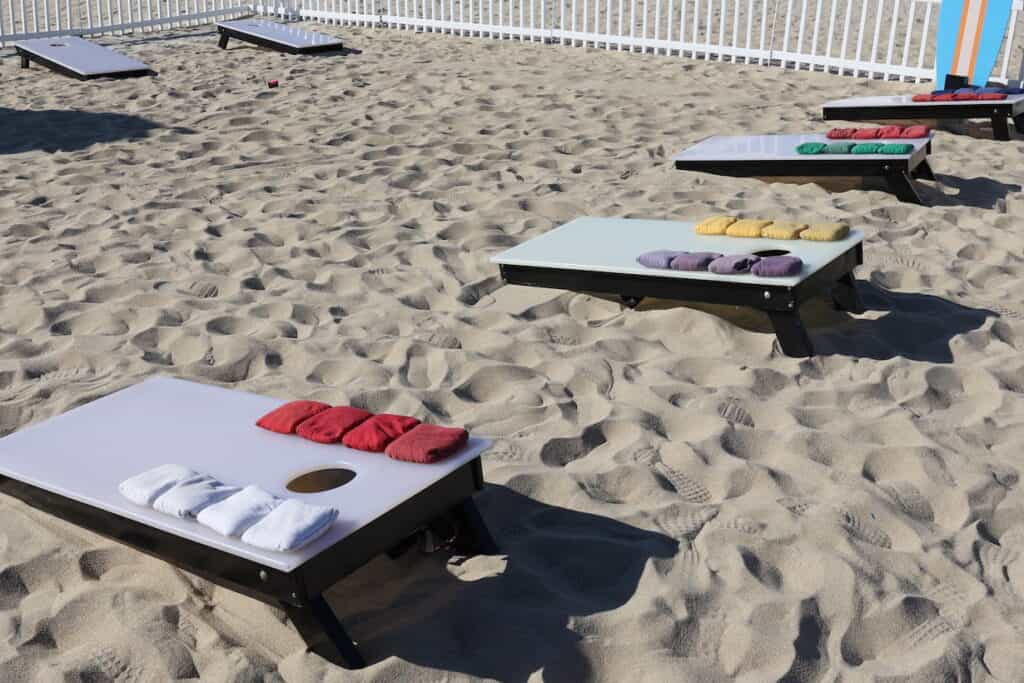 Cornhole boards scattered on the sandy beach.