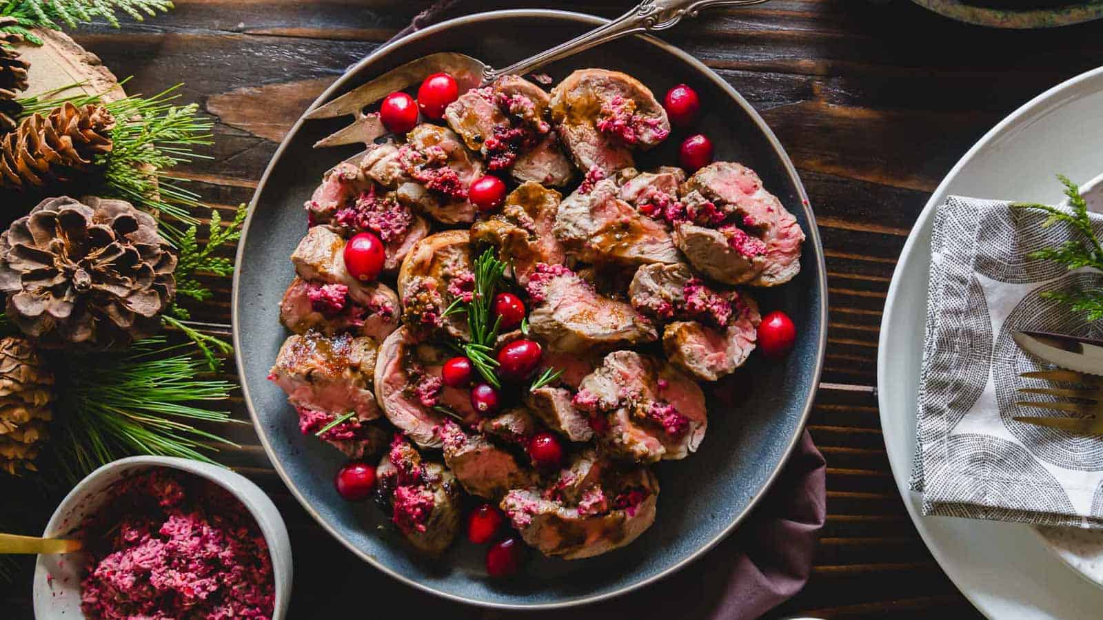 Cranberry pesto stuffed lamb sliced on a plate with a serving fork.