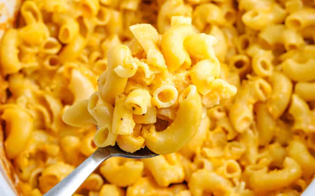 A spoonful of pasta macaroni and cheese in a slow cooker.