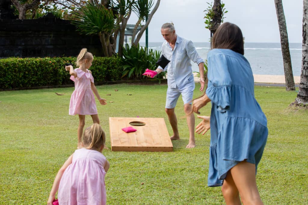 A group of people enjoying a game of cornhole.