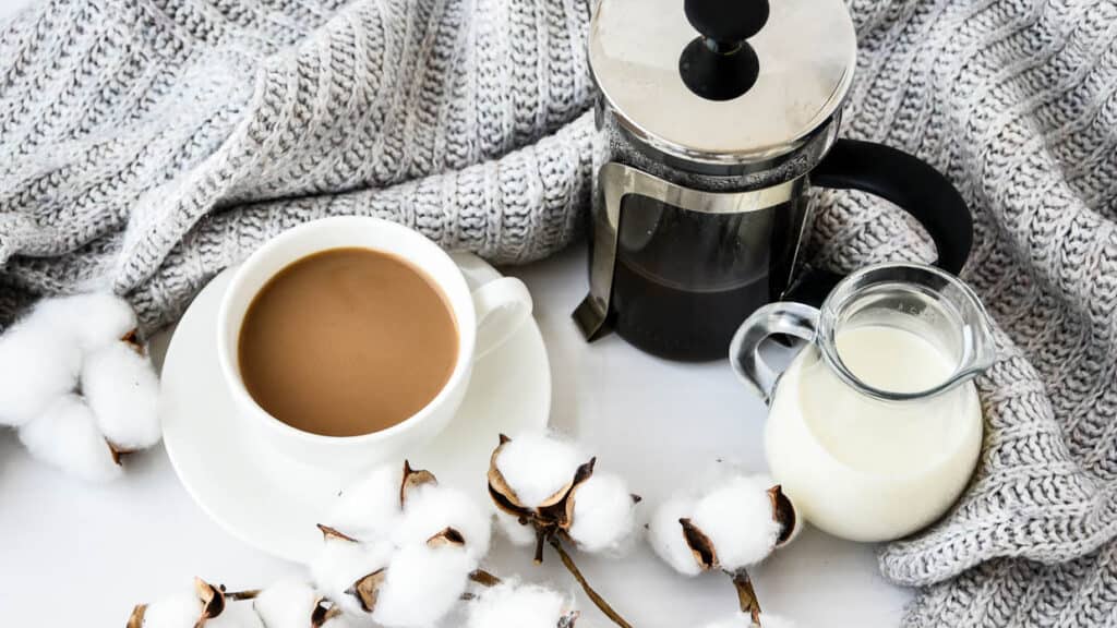 A cup of coffee and cotton on a white table.