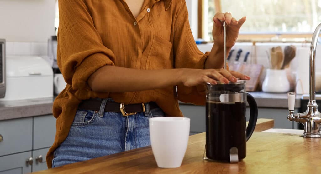 A woman pouring coffee into a french press.