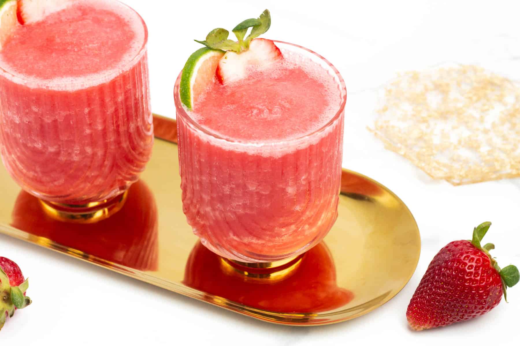 Two frozen strawberry daiquiris on a gold tray.