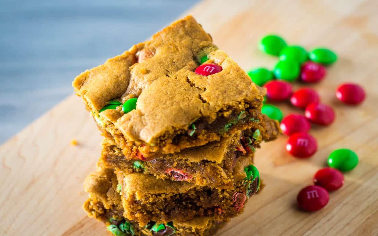 A stack of gingerbread cookie bars with m&m's on top.