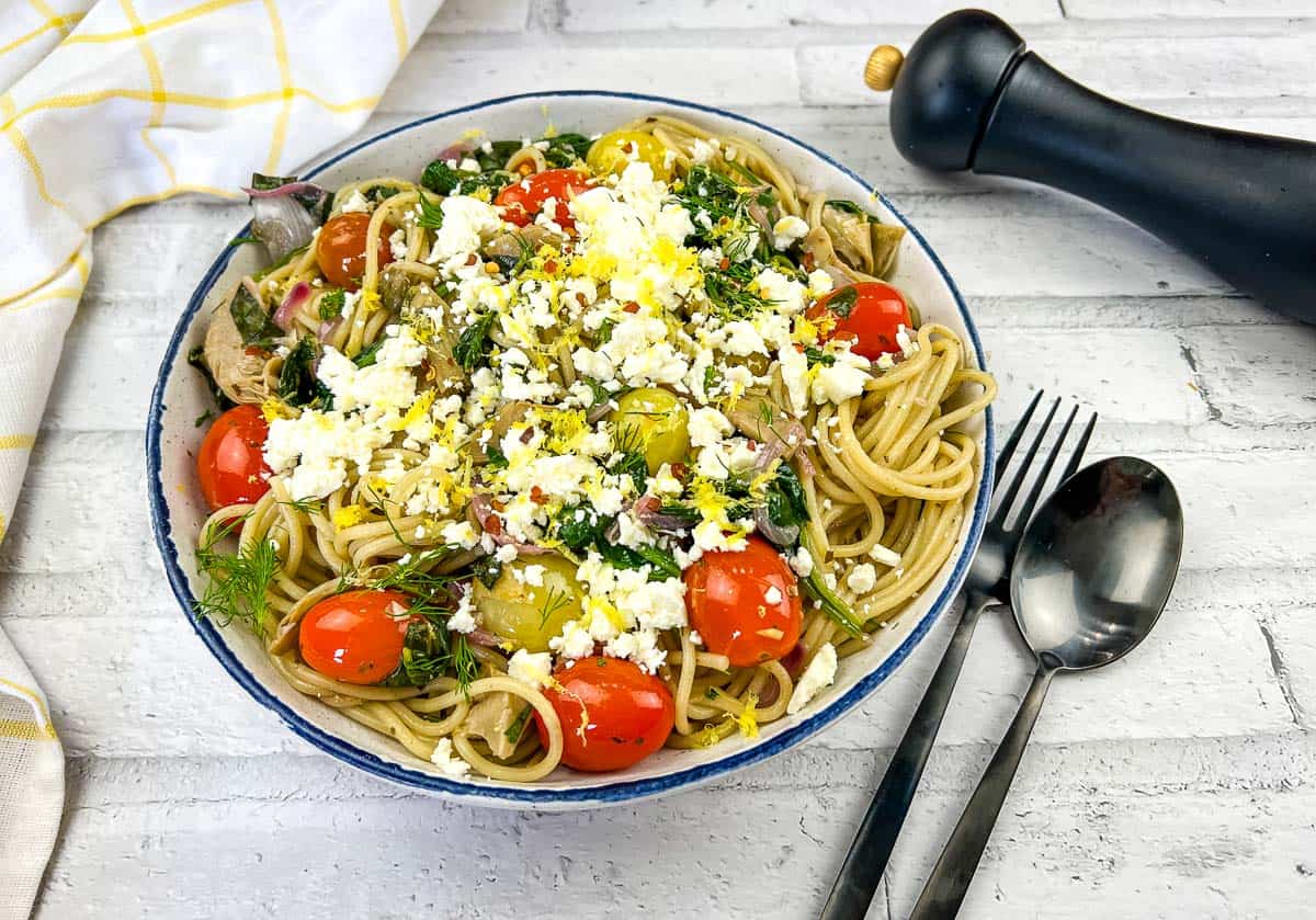 A bowl of pasta with tomatoes, feta and kalamata olives.