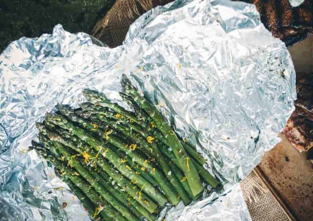 Asparagus wrapped in foil on a grill.