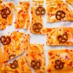 Orange pretzel bark with pretzels on a marble countertop.