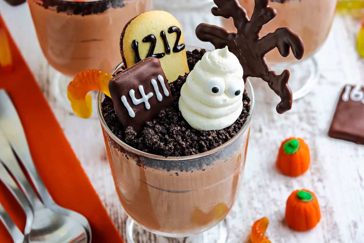 Halloween pudding dirt cup decorated with candy and cookies.