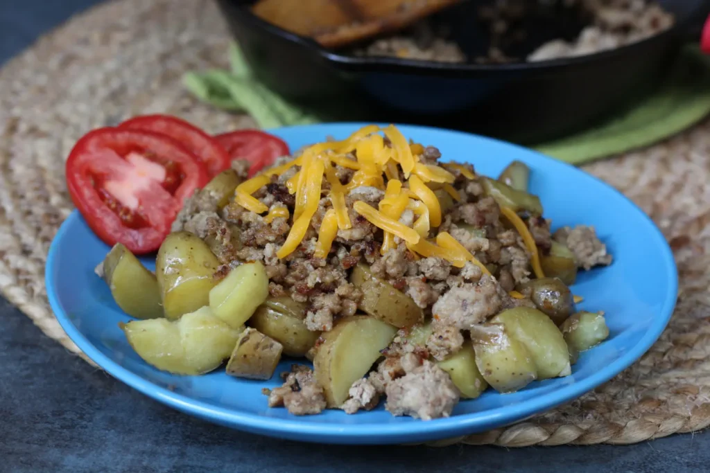 A blue plate with meat, potatoes and tomatoes.