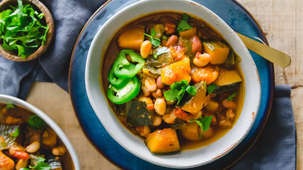 A bowl of kabocha squash chili in a bowl on a blue plate.