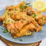 Chicken wings on a plate with lemon wedges.