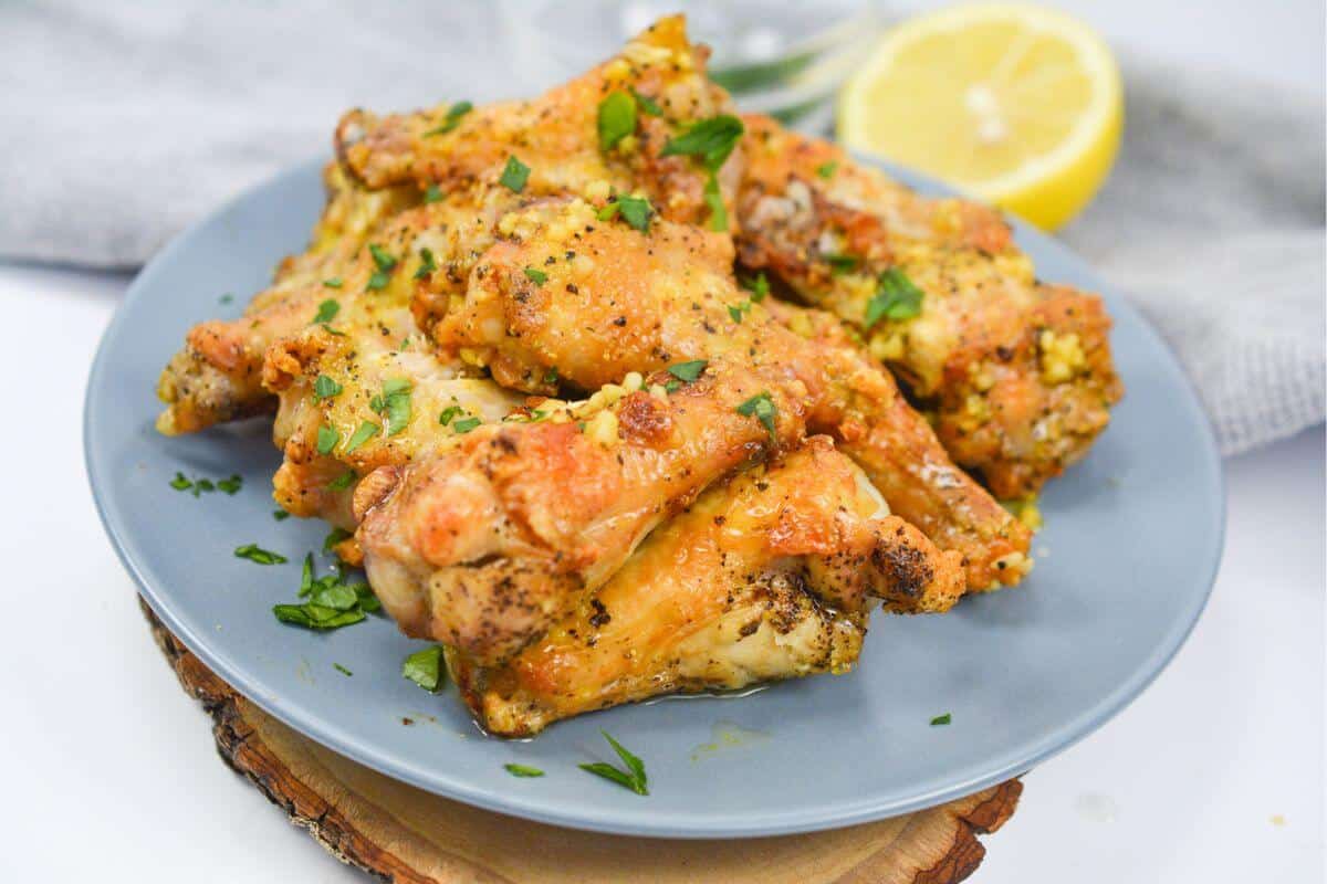 Chicken wings on a plate with lemon wedges.