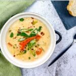 A bowl of lobster chowder with bread on the side.