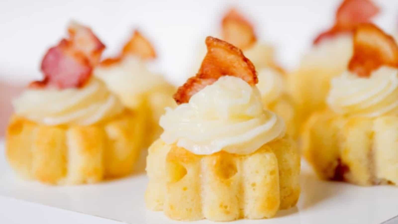 Several mini maple cupcakes with a slice of bacon on top.
