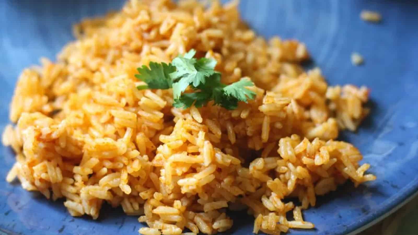 Gray bowl of Mexican rice with a spoon on a wooden background.