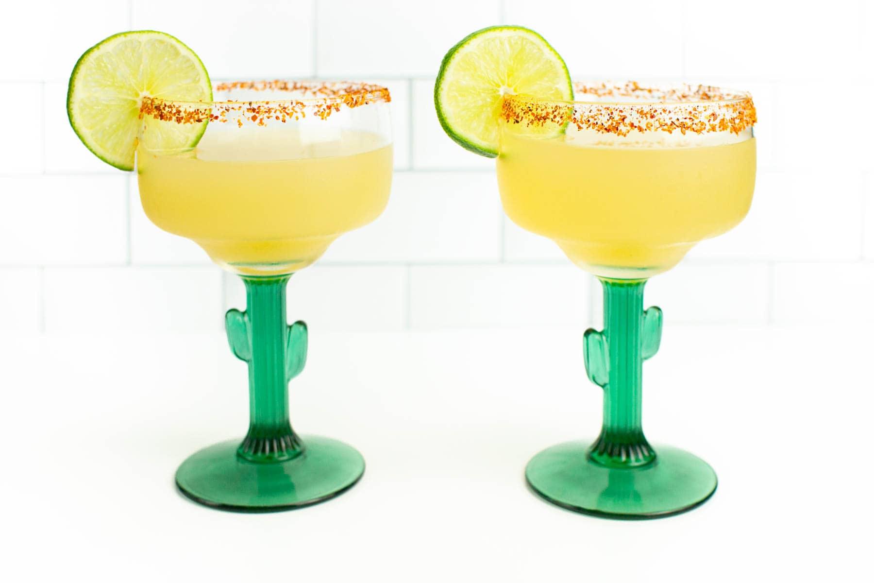 Two margarita glasses with lime and cactus garnish.