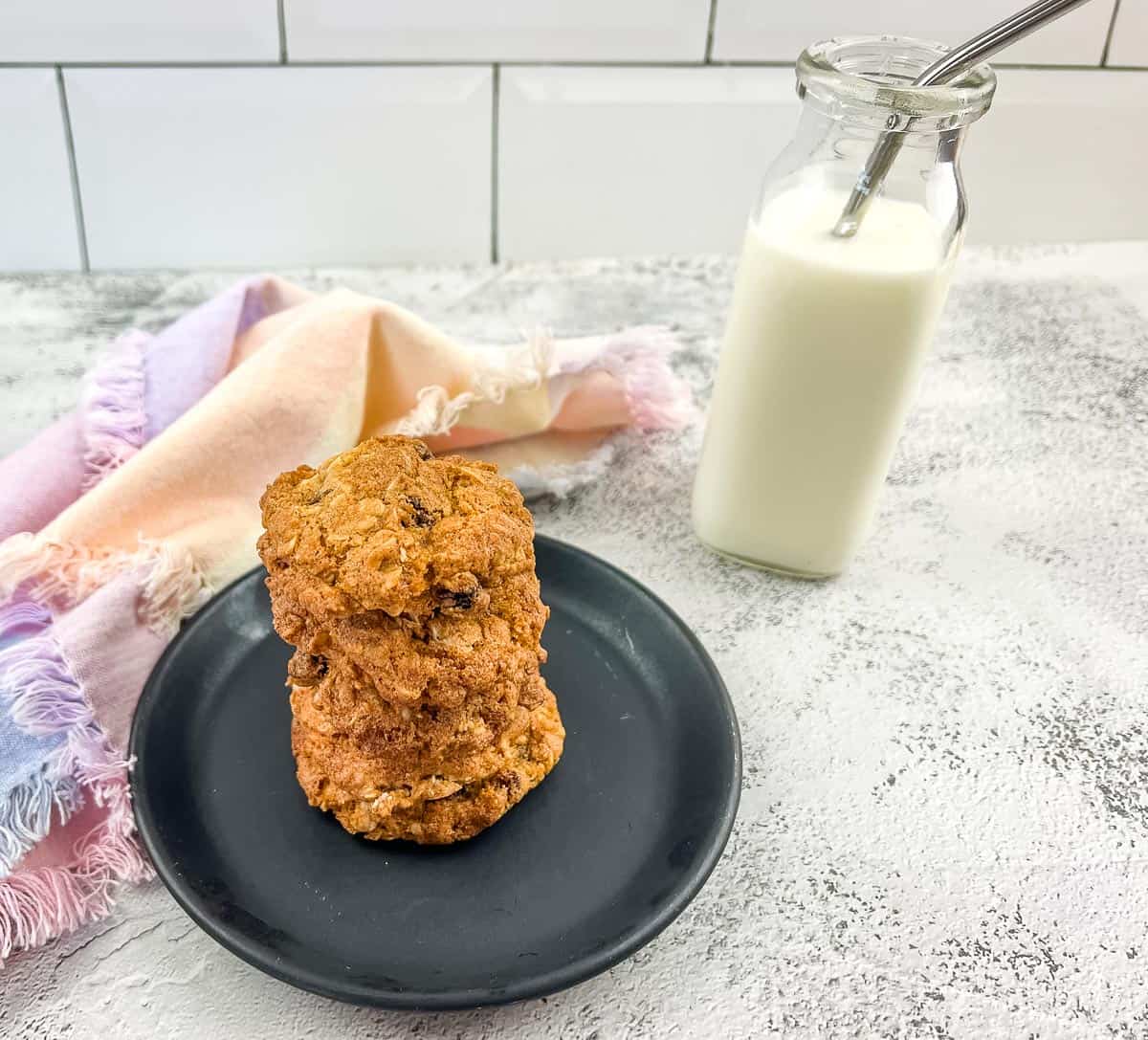 Oatmeal raisin cookies on a plate next to a glass of milk.