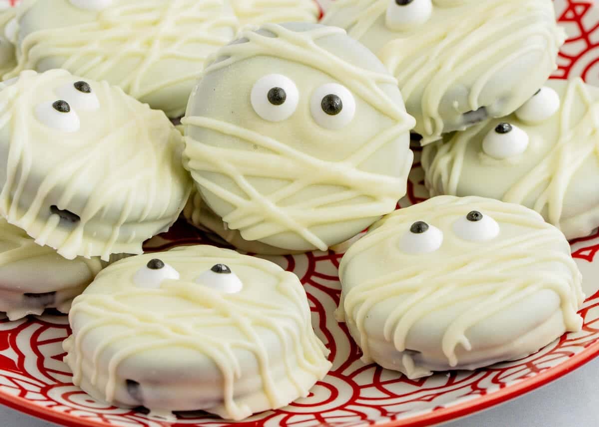 Mummy cookies on a red plate with eyes on them.
