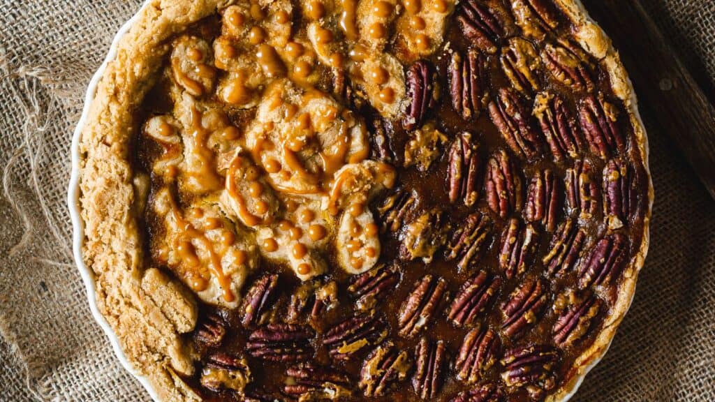 A pie with pecans and caramel on top.