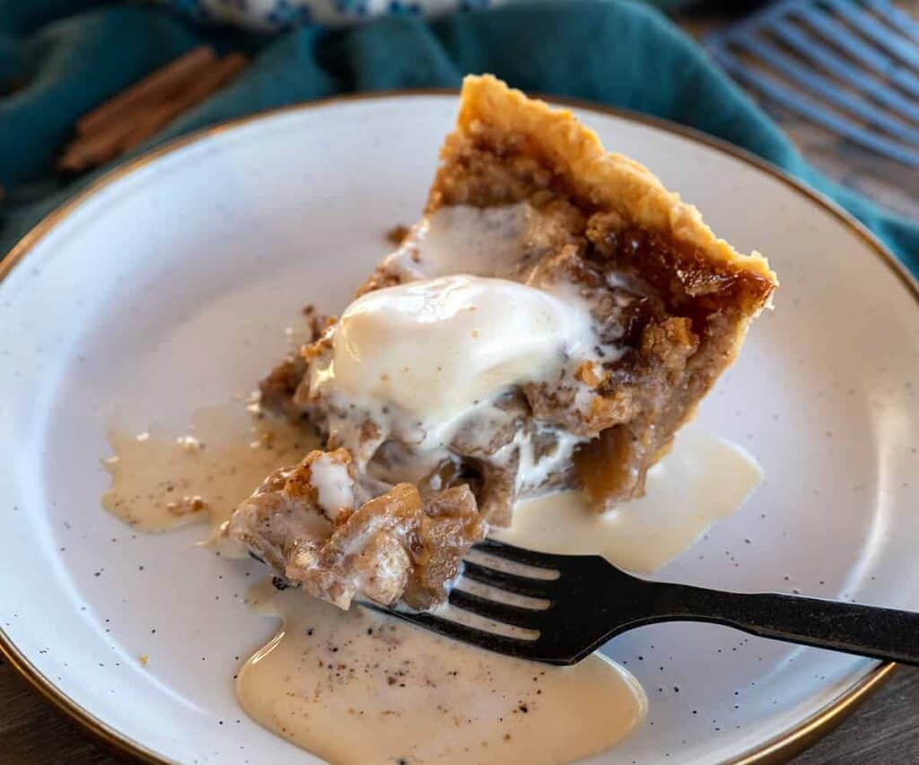 fork taking bite out of slice of apple pie.