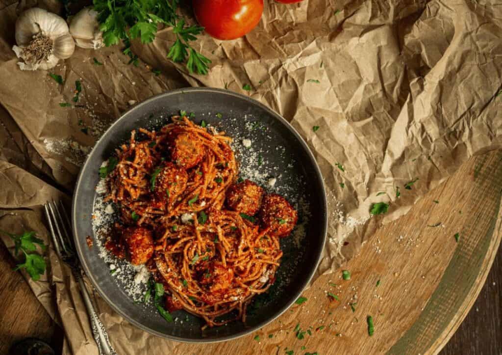 Spaghetti with meatballs and tomatoes on a wooden table.