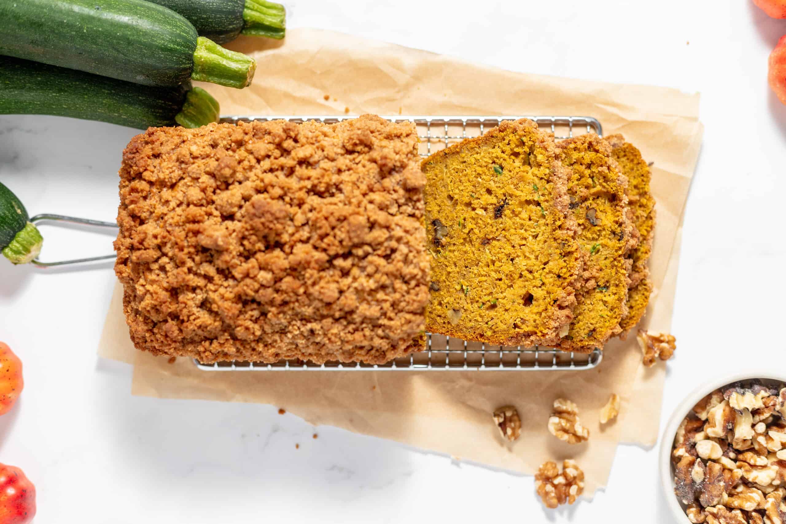 A loaf of pumpkin zucchini bread is sitting on a cooling rack.