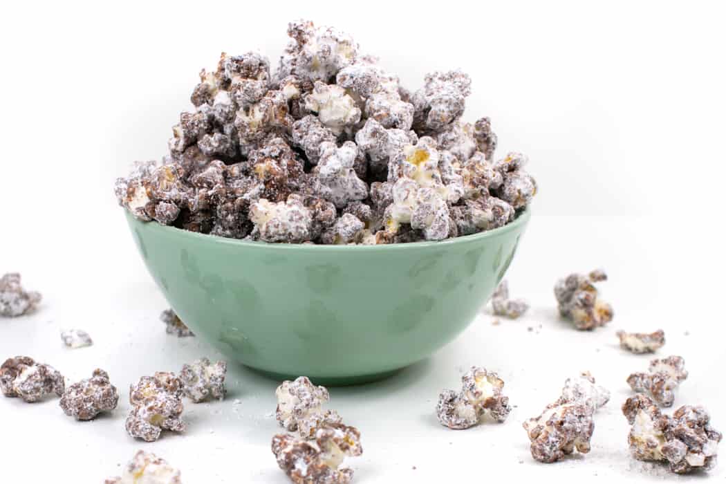 Kernels of Puppy Chow Popcorn spilling out of a mint green bowl.