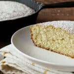 A slice of cake with powdered sugar on a plate.