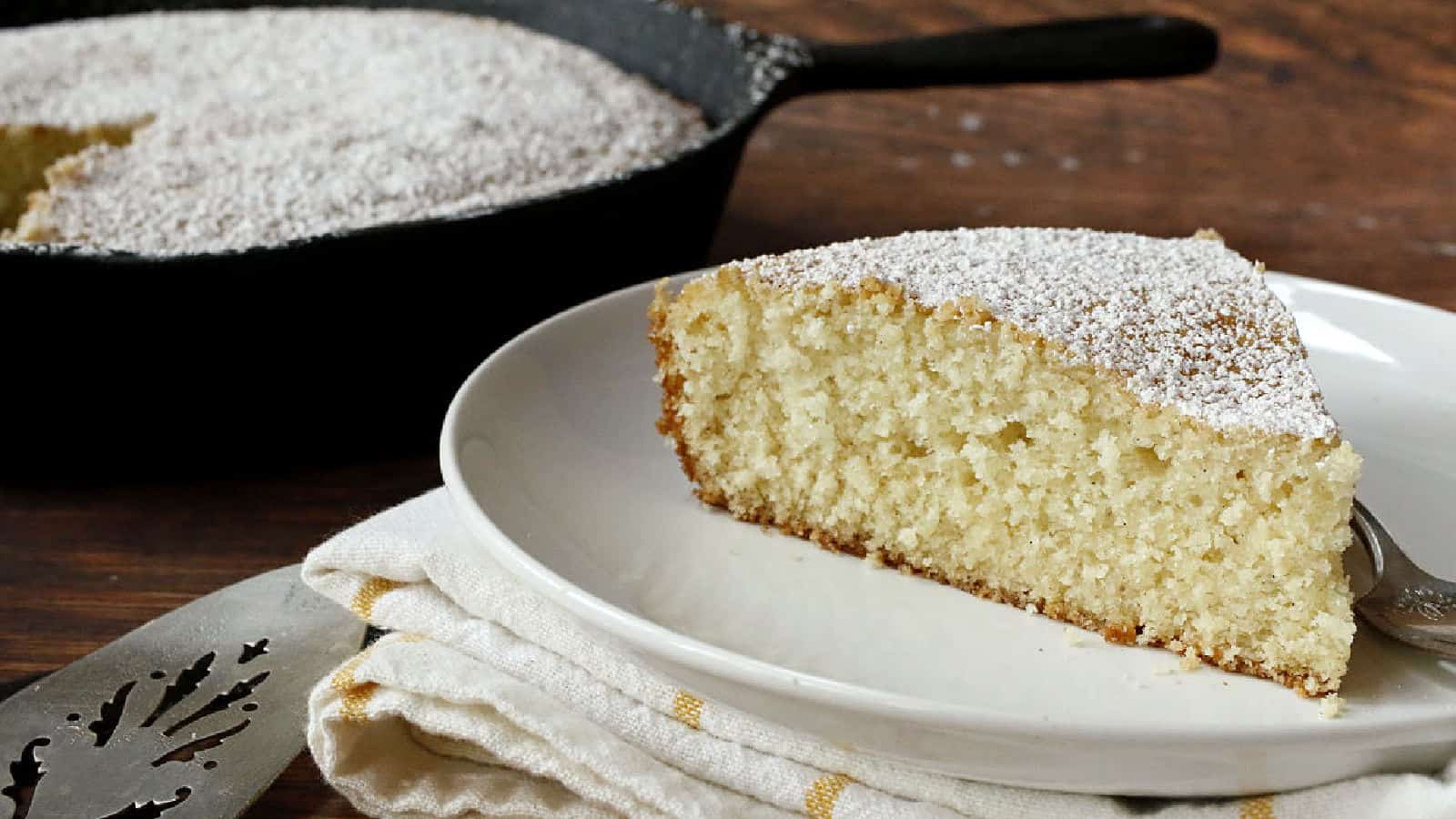A slice of cake with powdered sugar on a plate.