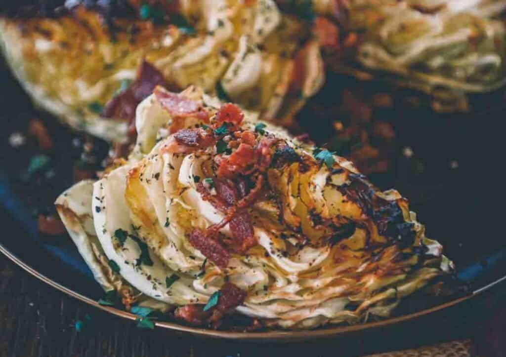 Roasted cabbage with bacon and parsley on a plate.