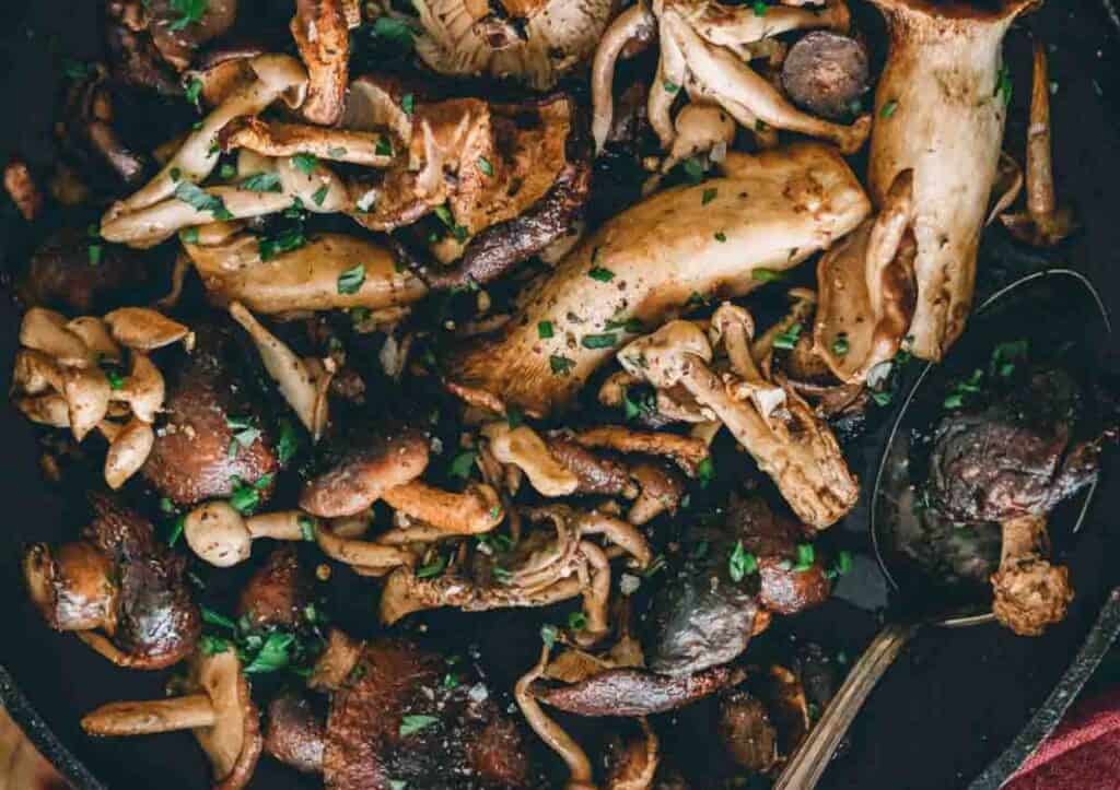 Roasted mushrooms in a skillet with a spoon.