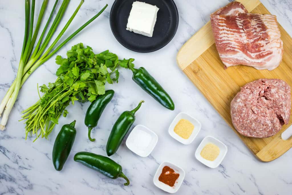 A cutting board with meat, jalapeos, and other ingredients.