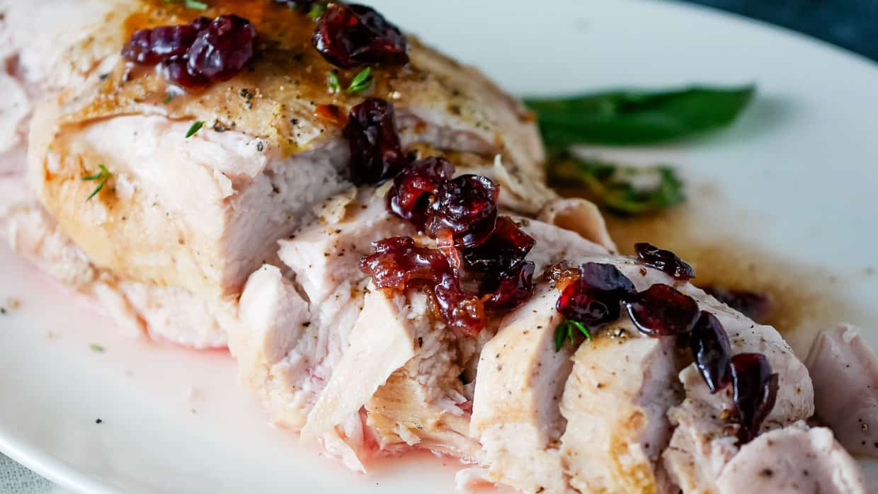 Roasted turkey with cranberry sauce on a white plate.