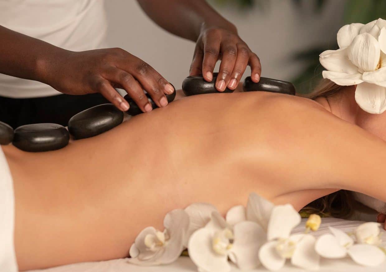 A woman getting a back massage with hot stones.