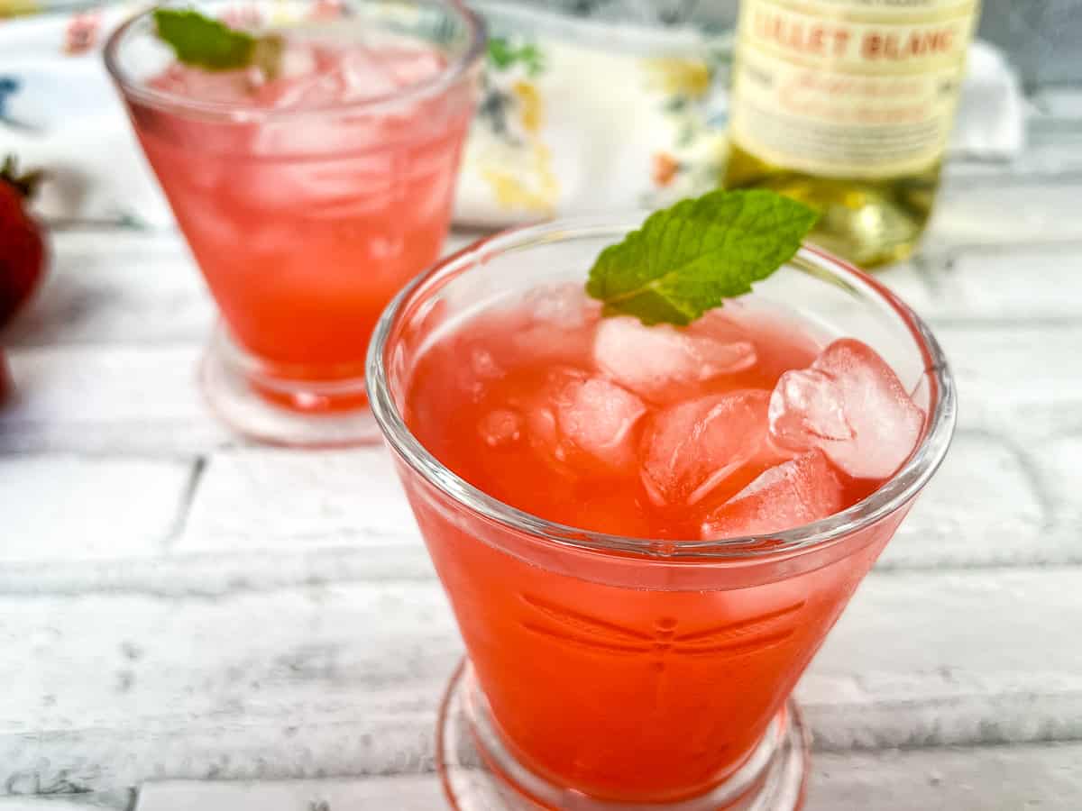 Two glasses of strawberry lillet crush with mint leaves.