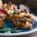 Stuffing muffins on a plate with apples, cranberries, sausage and sage.