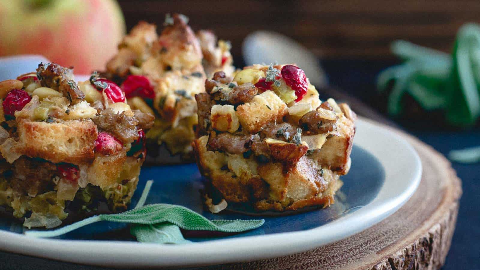 Stuffing muffins on a plate with apples, cranberries, sausage and sage.